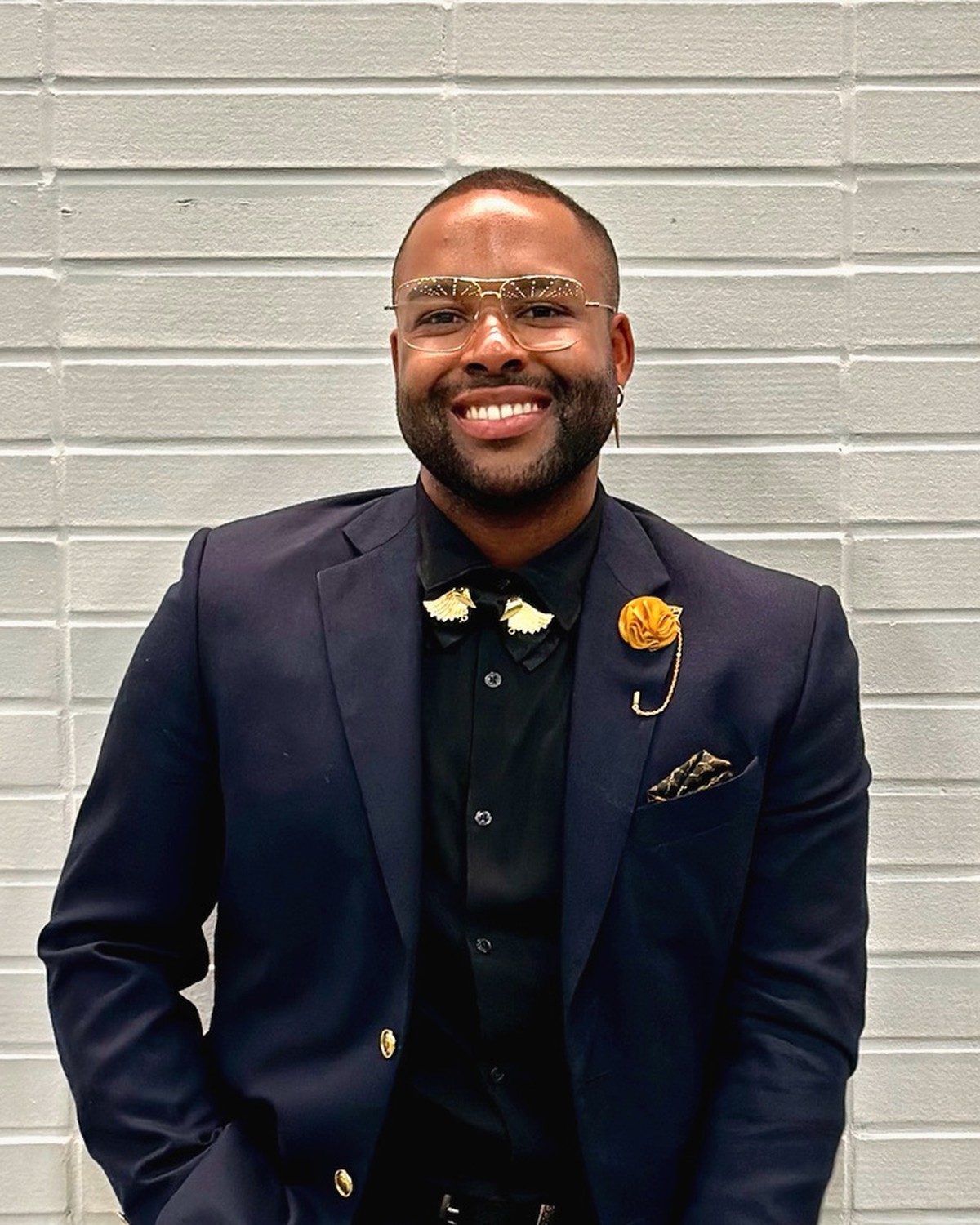Logan Golden, Licensed Professional Counselor, smiling in a navy blazer against a light brick wall